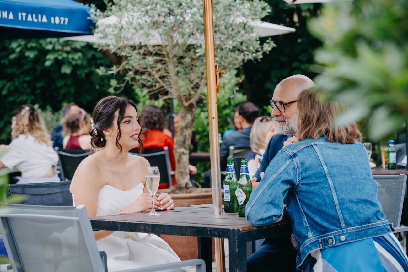Bride chatting with wedding guests over drinks on the terrace at the Old Post House in St Fagans