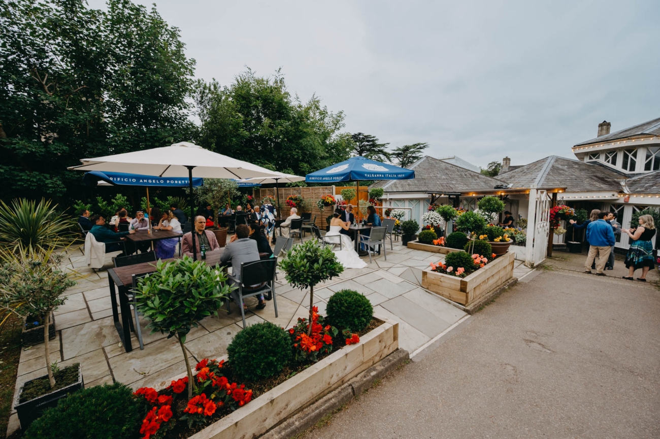 Wedding guests enjoying drinks on the flower-filled terrace at the Old Post House in St Fagans