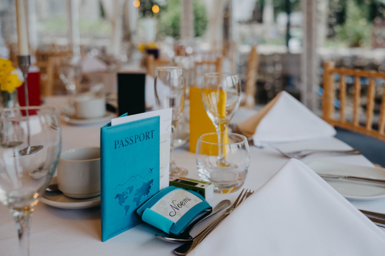 Wedding table setting with a passport-style favour and a glass of orange juice inside the Old Post House marquee