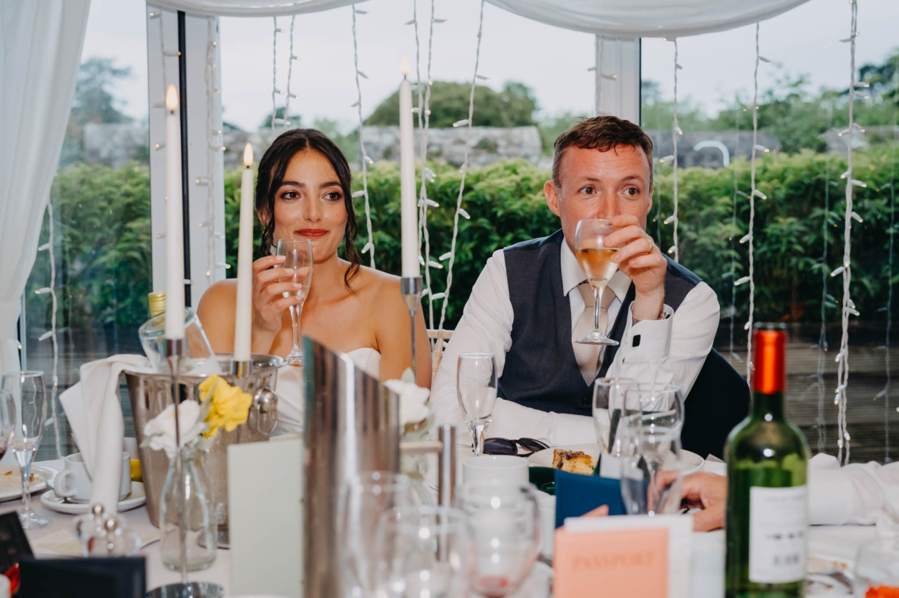 Bride and groom holding drinks at the top table during their Old Post House wedding reception