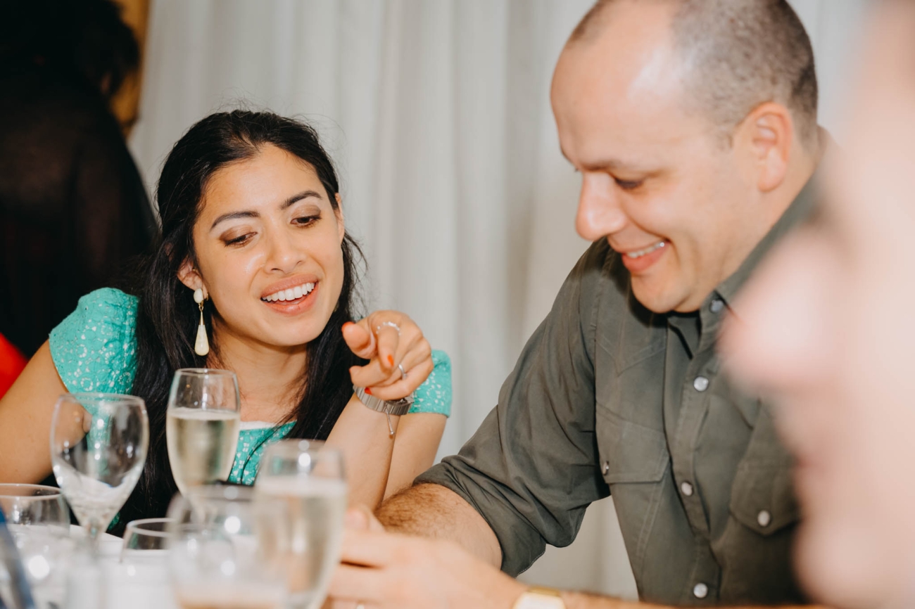 Wedding guest pointing as she shares a lively conversation across the table