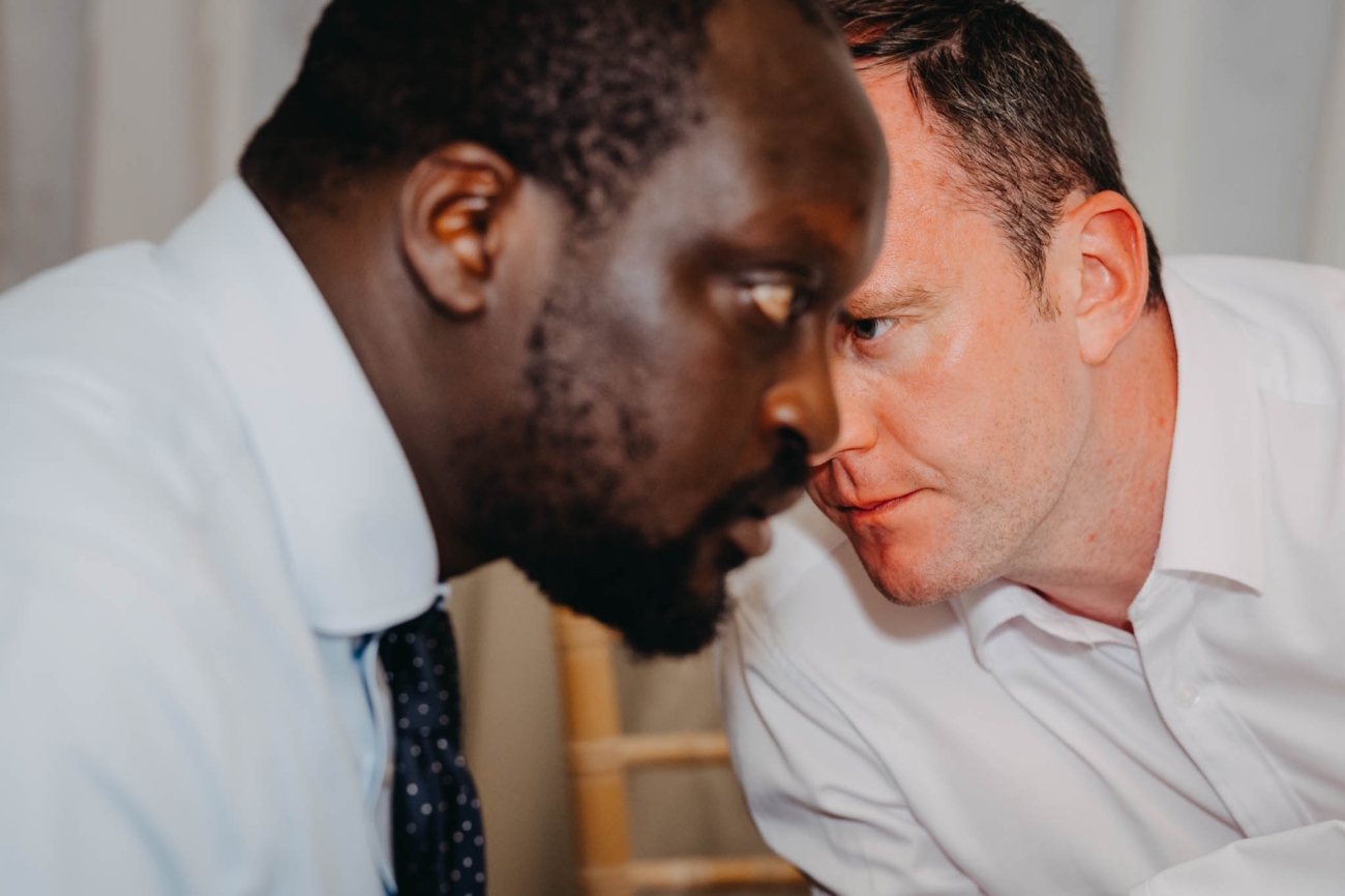 Two wedding guests leaning close to talk during the Old Post House reception