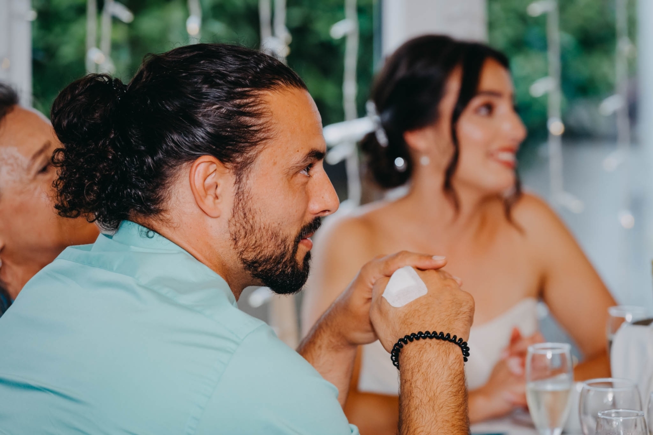 Wedding guest listening to the speeches with the bride smiling in the background