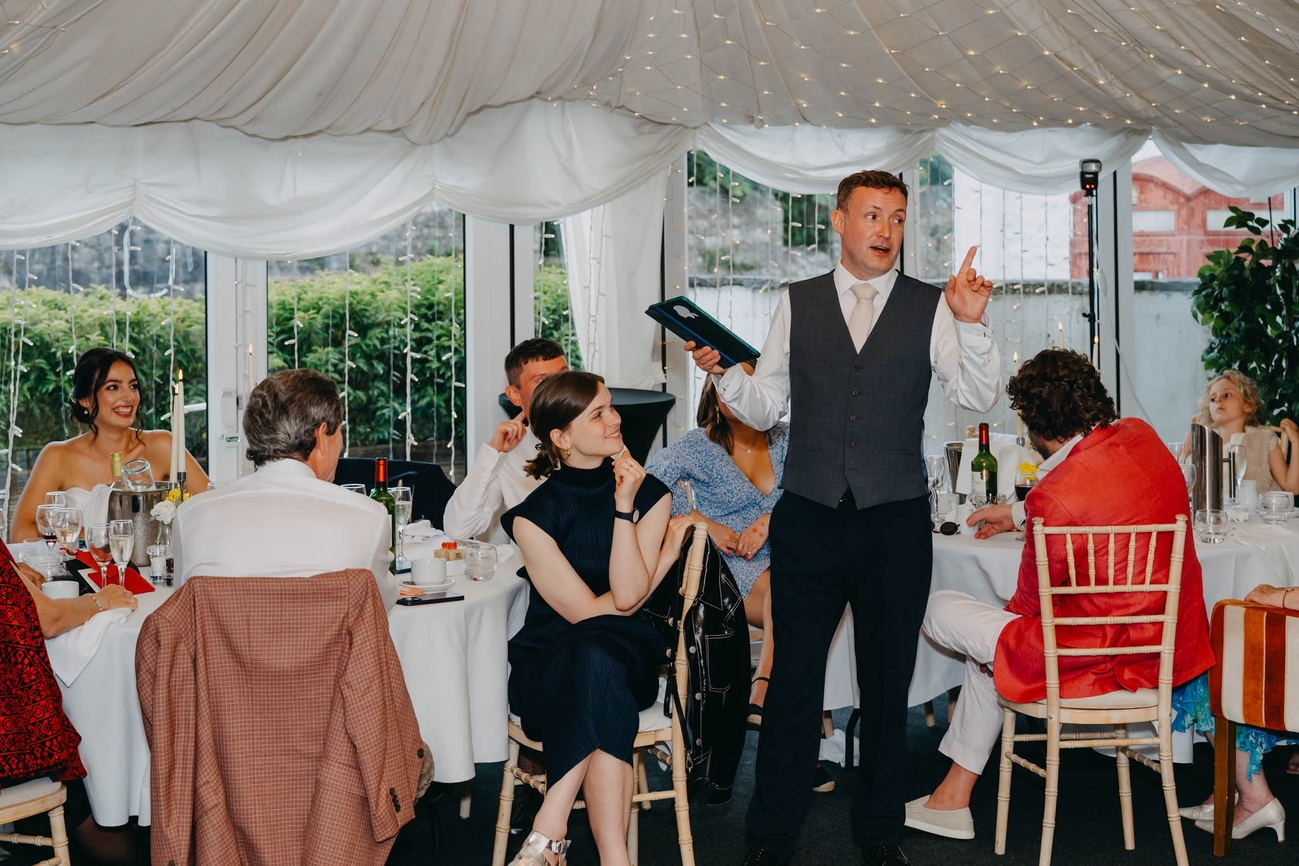 Groom giving his wedding speech as the bride and guests smile at the Old Post House in St Fagans