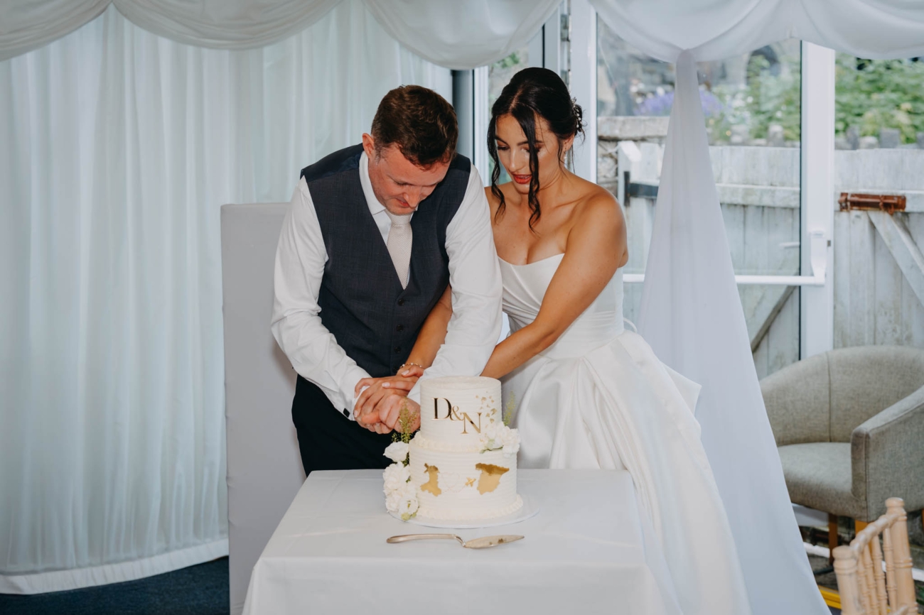 Bride and groom cutting their two-tier wedding cake together at the Old Post House