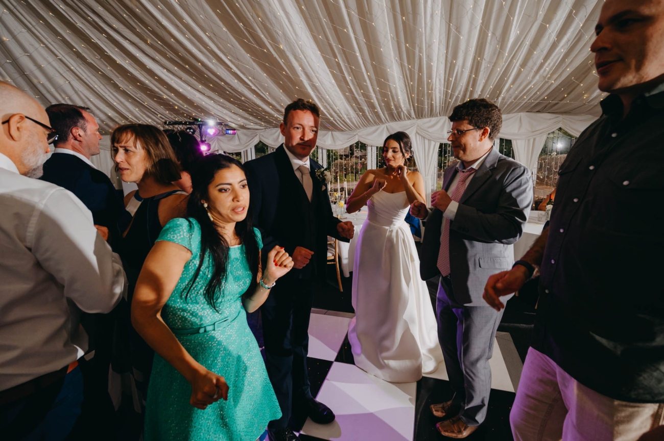 Bride and wedding guests dancing together as the evening party gets under way
