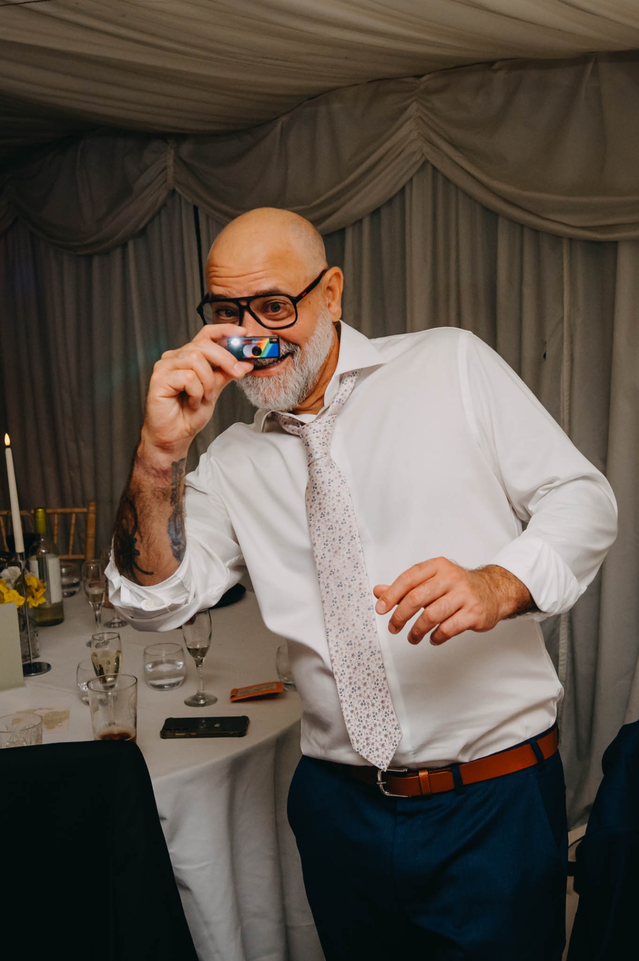 Wedding guest holding a miniature camera beneath his nose on the dance floor