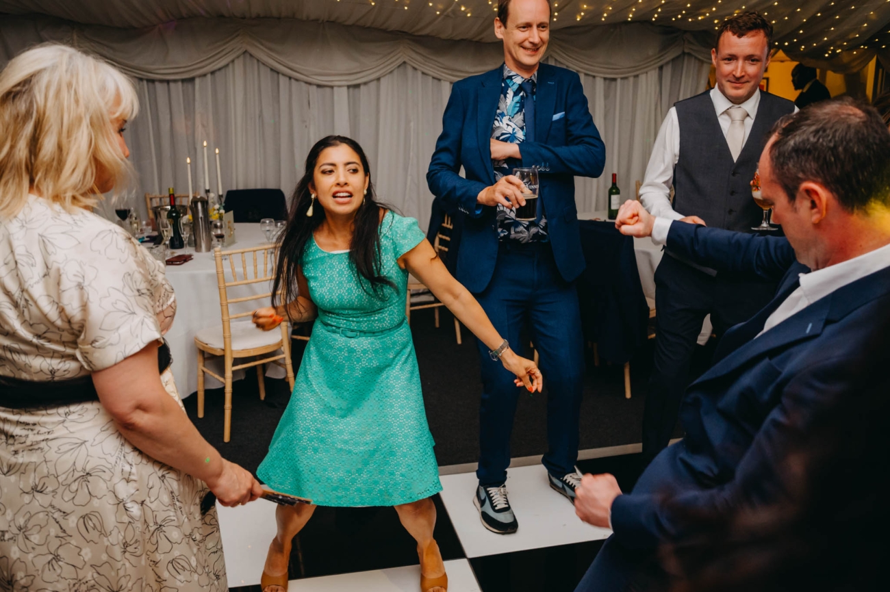 Wedding guests holding hands in a circle while dancing at the evening reception