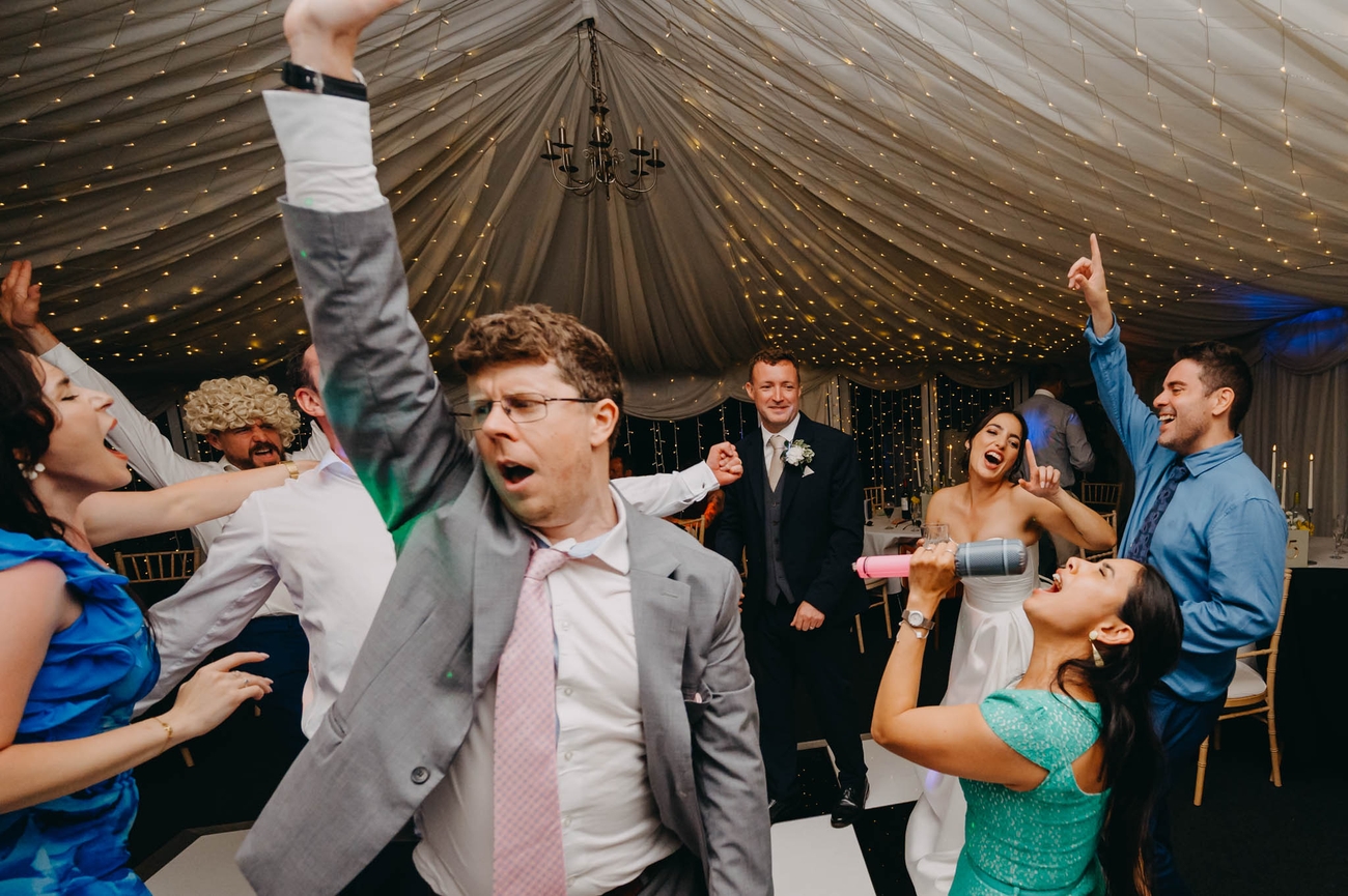 Wedding guests dancing and singing with the bride and groom during the evening reception at the Old Post House in St Fagans
