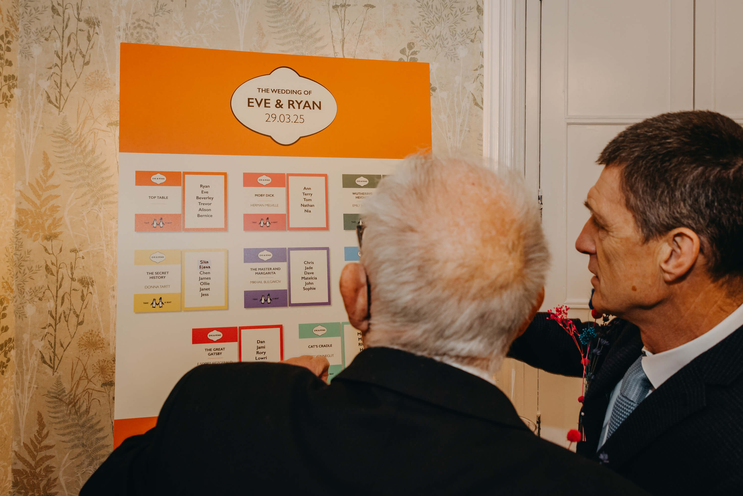 Wedding guests checking a literary-themed seating plan to find their tables at a wedding in South Wales