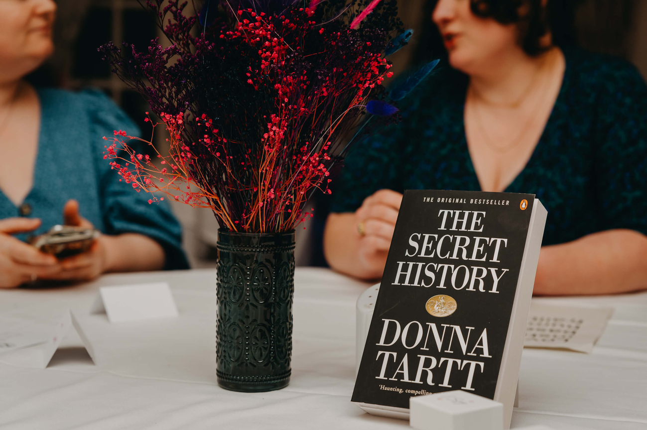 The Secret History by Donna Tartt displayed among colourful dried flowers as part of a literary-themed wedding table